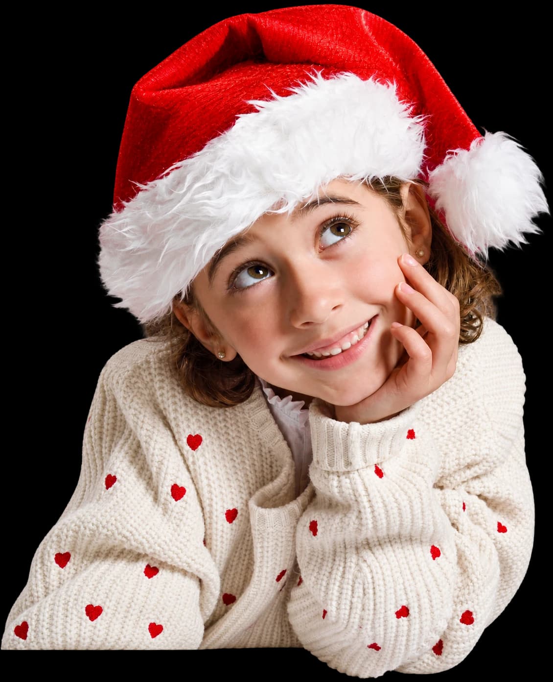 Une petite fille en bonnet de Noël, rêveuse, la joue dans la main